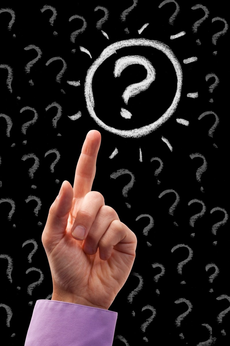 Hand zeigt auf ein Fragezeichen als Symbol für Entscheidung und Reflexion im Coaching.